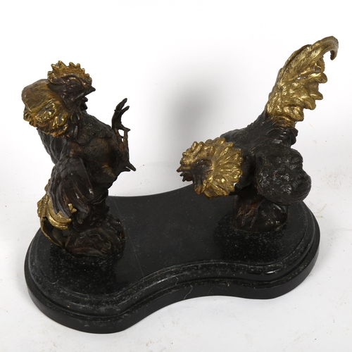 551 - A contemporary parcel gilt and patinated bronze sculpture of fighting cockerels, on shaped marble ba... 