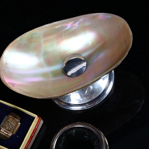 1342 - A mother-of-pearl table salt on silver stand, a silver napkin ring, and a silver signet ring (3)