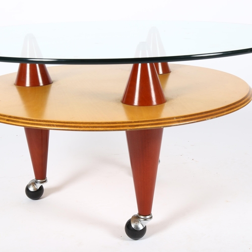 1517 - SANTA & COLE, a post-modern coffee table, with glass top on conical supports and ball casters, diame... 