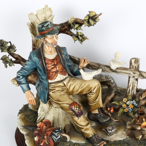 566 - A Capodimonte tableau, man with birds, on wooden plinth, height 26cm