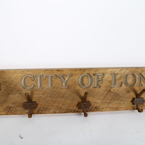 571 - A wall-mounted coat rack, inscribed and carved and painted City of London Underground signs, 105cm