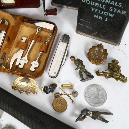 185 - A box containing various military badges and tins, a fireman's axe, a leather multi-tool set etc