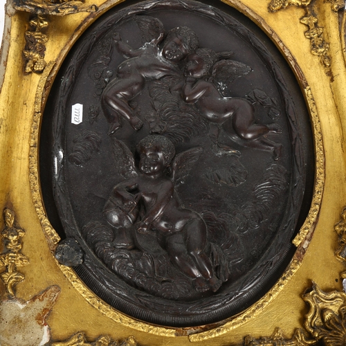 688 - A patinated metal plaque of 3 cherubs, gilt-framed (frame A/F), overall length 51cm