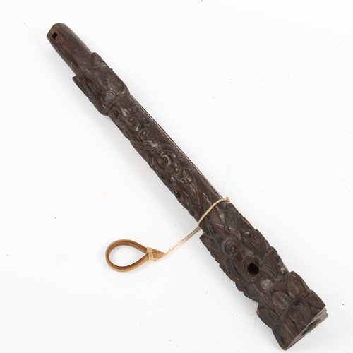 1074 - An Oriental carved hardwood flute with mask designs, length 35cm