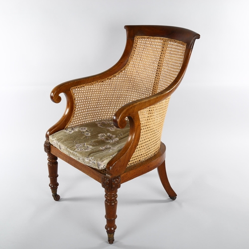 1232 - A 19th century mahogany-framed Bergere tub chair, on turned legs, with squab seat and brass casters