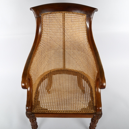 1232 - A 19th century mahogany-framed Bergere tub chair, on turned legs, with squab seat and brass casters