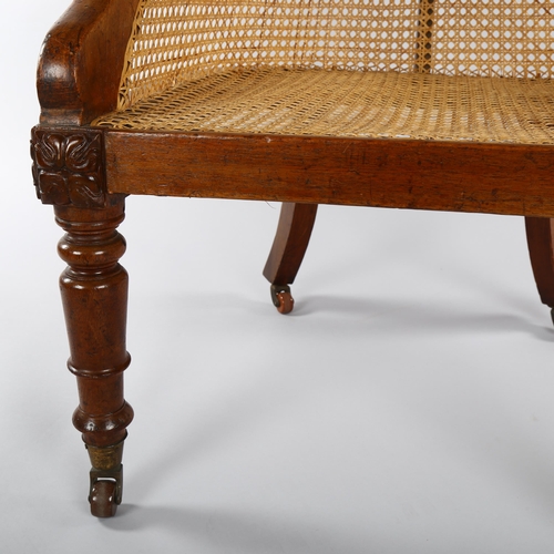 1232 - A 19th century mahogany-framed Bergere tub chair, on turned legs, with squab seat and brass casters