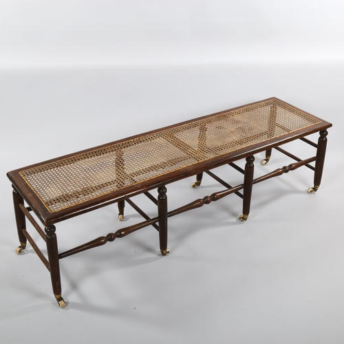 1234 - A Victorian window seat with cane panel, turned spindles and original casters, length 137cm