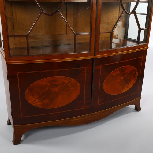 1235 - An Edwardian inlaid mahogany bow-front display cabinet in Sheritan style, with carved cornice and cu... 