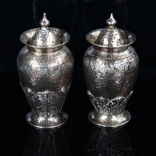 423 - A pair of Arts and Crafts Edwardian silver pepperettes, planished and relief embossed acanthus leaf ... 