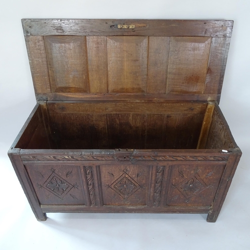 2058 - An Antique panelled oak coffer with carved decoration, on stile legs, 125cm x 67cm x 53cm