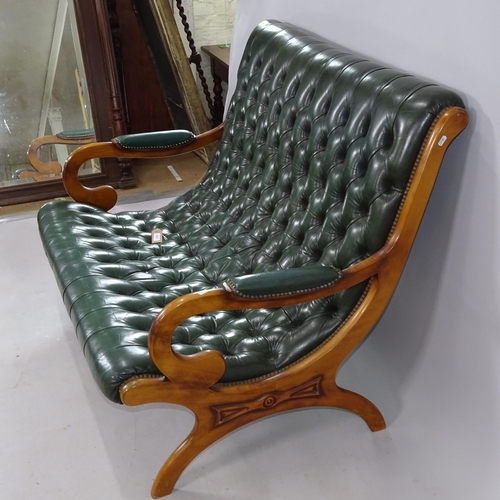 2257 - A studded green leather upholstered 2-seater settee, on X-framed legs, 118cm x 95cm x 90cm