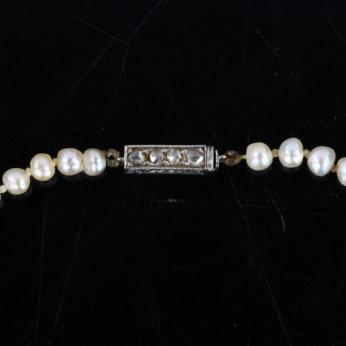 149 - A natural pearl necklace, the 129 graduated pearls measuring 6.6mm - 7.2mm to 3.3mm, to a rose-cut d... 