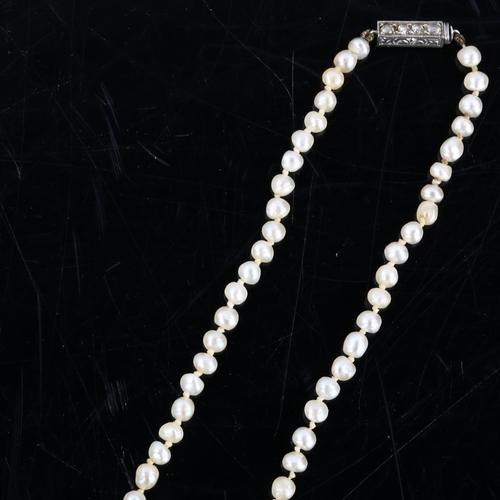 149 - A natural pearl necklace, the 129 graduated pearls measuring 6.6mm - 7.2mm to 3.3mm, to a rose-cut d... 