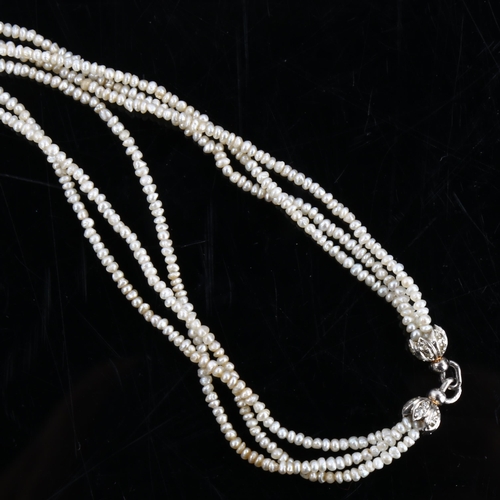 151 - A long triple-strand seed pearl torsade necklace, with unmarked white metal old-cut diamond set clas... 