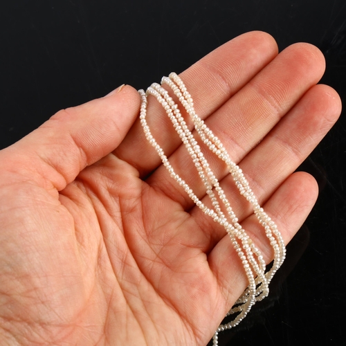 151 - A long triple-strand seed pearl torsade necklace, with unmarked white metal old-cut diamond set clas... 