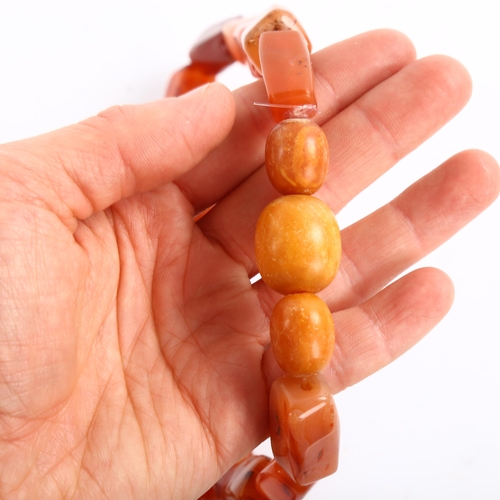 207 - A carnelian and butterscotch amber bead necklace, largest amber bead length 21.4mm, necklace length ... 