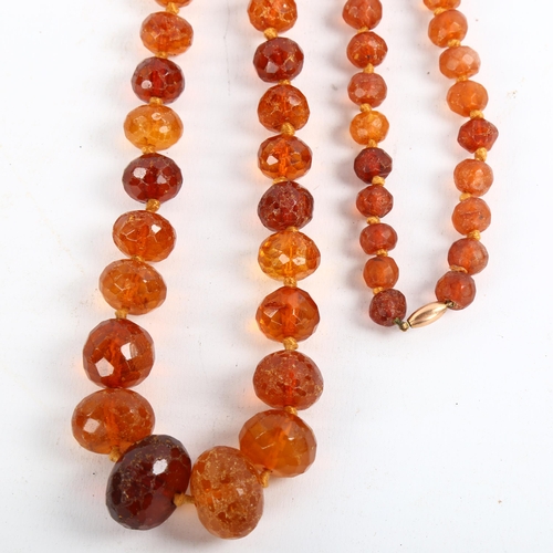 209 - A long graduated faceted amber bead necklace, with unmarked rose gold barrel clasp, beads ranging fr... 