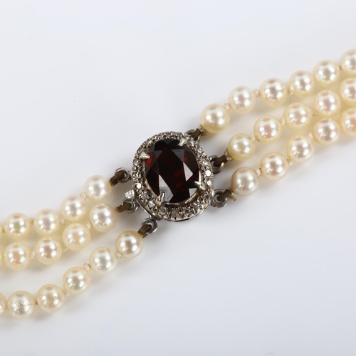 283 - A Vintage triple-strand pearl necklace, with unmarked white metal garnet and diamond cluster clasp, ... 