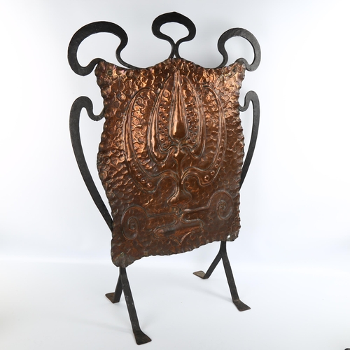 1064 - An Arts and Crafts wrought-iron and copper fire screen, with embossed panel, unsigned, height 78cm