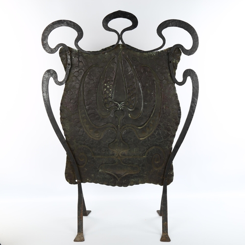 1064 - An Arts and Crafts wrought-iron and copper fire screen, with embossed panel, unsigned, height 78cm