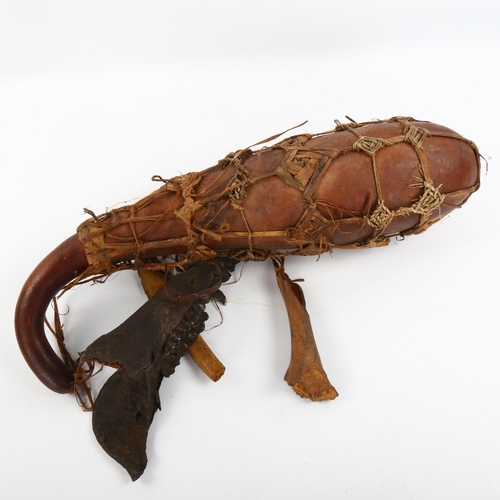 1083 - A Tribal witch doctor gourd, sinew-bound with animal and bone attachments, length 43cm