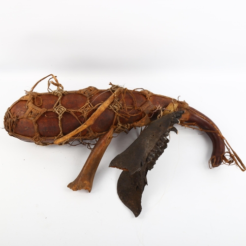 1083 - A Tribal witch doctor gourd, sinew-bound with animal and bone attachments, length 43cm