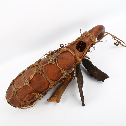 1083 - A Tribal witch doctor gourd, sinew-bound with animal and bone attachments, length 43cm