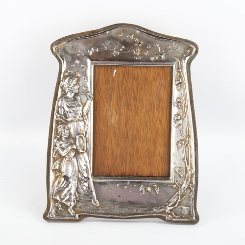 1085 - An Art Nouveau electroplate photo frame, relief moulded decoration depicting a woman and child, oak ... 