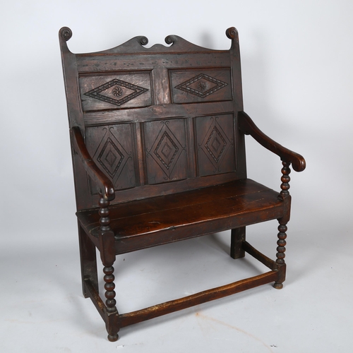 1133 - An 18th century oak settle of small size, with lozenge carved 5-panel back and bobbin turned support... 