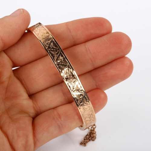 369 - An early 20th century 9ct rose gold hinged bangle, with engraved leaf decoration, maker's marks S Br... 