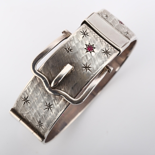 370 - A heavy mid-20th century silver ruby belt buckle hinged bangle, with textured ground and star motif,... 