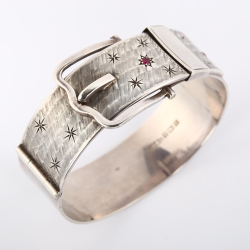 370 - A heavy mid-20th century silver ruby belt buckle hinged bangle, with textured ground and star motif,... 