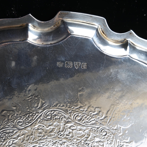 544 - A George V silver salver, circular form with scalloped rim and Indian inspired engraved animal decor... 