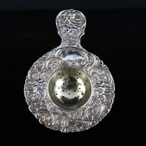 578 - A large German silver tea strainer, with relief embossed cherub and foliate decoration, length 14.5c... 