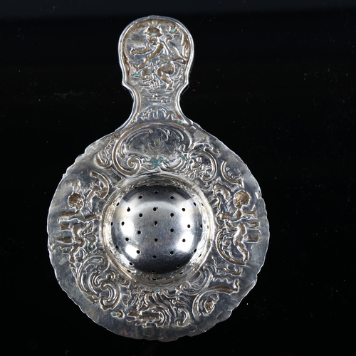 578 - A large German silver tea strainer, with relief embossed cherub and foliate decoration, length 14.5c... 