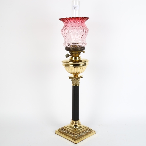 26 - An early 20th century brass duplex Corinthian column oil lamp, with cranberry glass shade and chimne... 