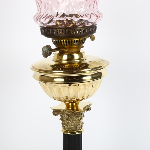26 - An early 20th century brass duplex Corinthian column oil lamp, with cranberry glass shade and chimne... 