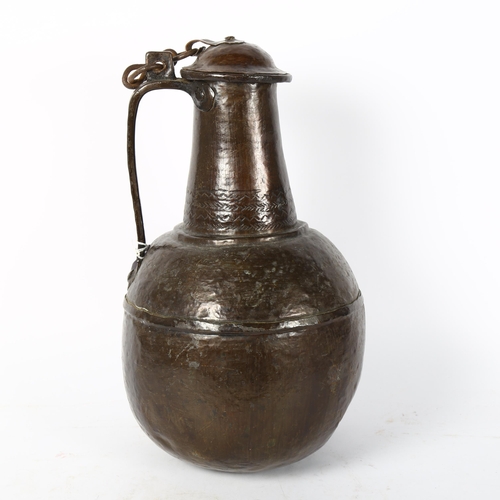56 - A Middle Eastern handmade copper wine flagon and cover, engraved geometric decoration to the lid, he... 