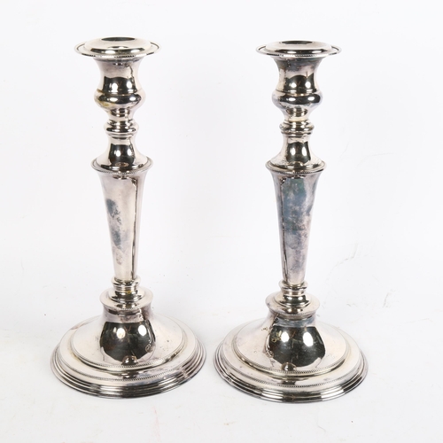 1001 - A pair of silver plate on copper candle stands of tapered form, on circular plinth base, height 28cm