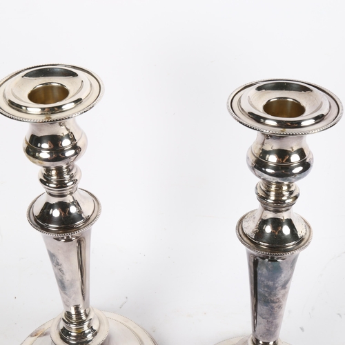 1001 - A pair of silver plate on copper candle stands of tapered form, on circular plinth base, height 28cm