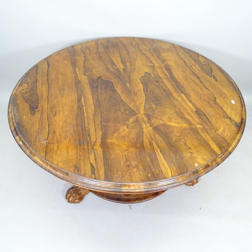 2528 - A 19th century rosewood tilt-top table, with circular base and lion paw feet, 130cm x 71cm