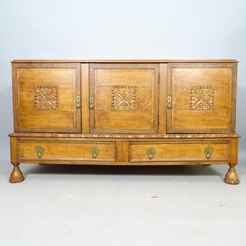 2567 - An Antique oak Arts and Crafts sideboard, with carved floral decoration, having 3 panelled doors and... 