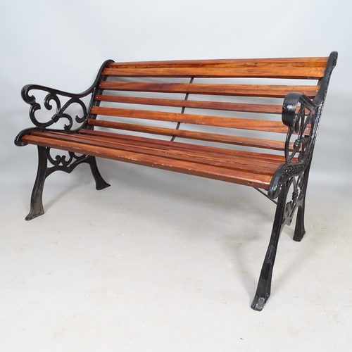 2587 - A stained teak slatted garden bench with cast-iron ends, L124cm