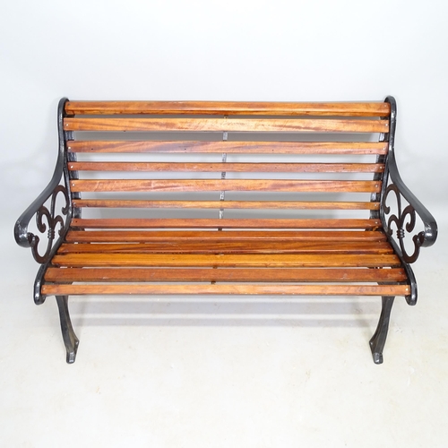 2587 - A stained teak slatted garden bench with cast-iron ends, L124cm