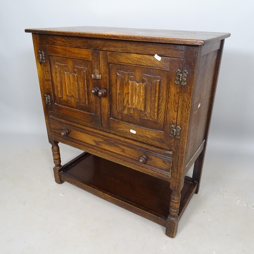 2633 - A 1930s oak hall cabinet, with linenfold panel doors, and single drawer under, 79cm x 85cm x 40cm