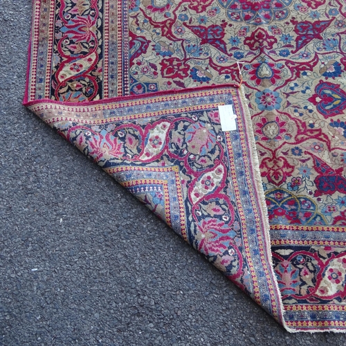 2426 - An Antique red ground Persian Isfahan rug, with repeating border and floral decorated square lozenge... 