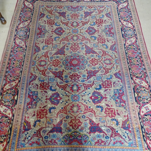 2426 - An Antique red ground Persian Isfahan rug, with repeating border and floral decorated square lozenge... 