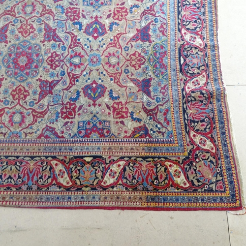 2426 - An Antique red ground Persian Isfahan rug, with repeating border and floral decorated square lozenge... 