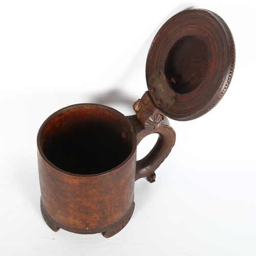 1001 - An 18th century Scandinavian birch peg tankard, with carved hinged lid, resting on 3 carved feet, he... 